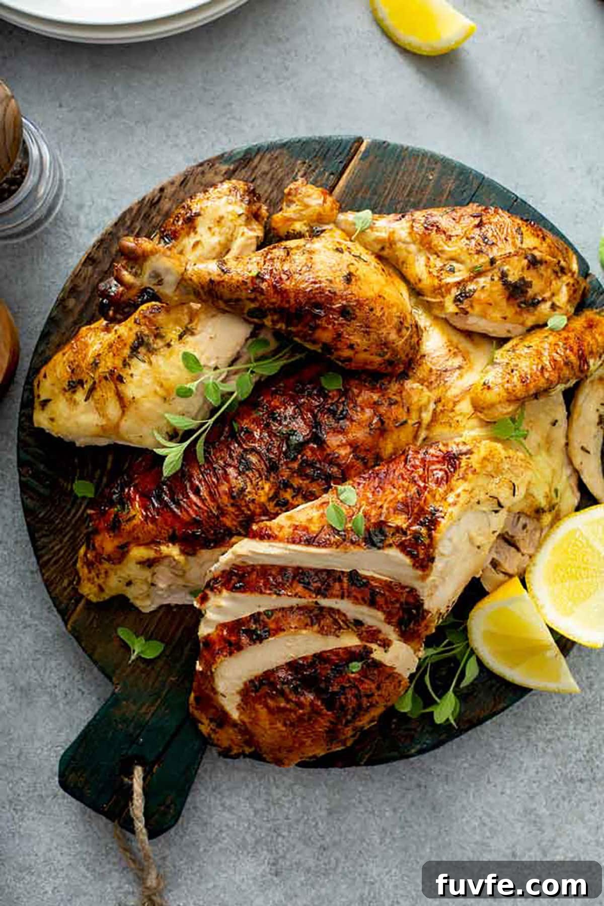 Herb-Butter Roast Chicken Recipe for Juicy Crispy Skin 11 Carved baked chicken on a round cutting board.