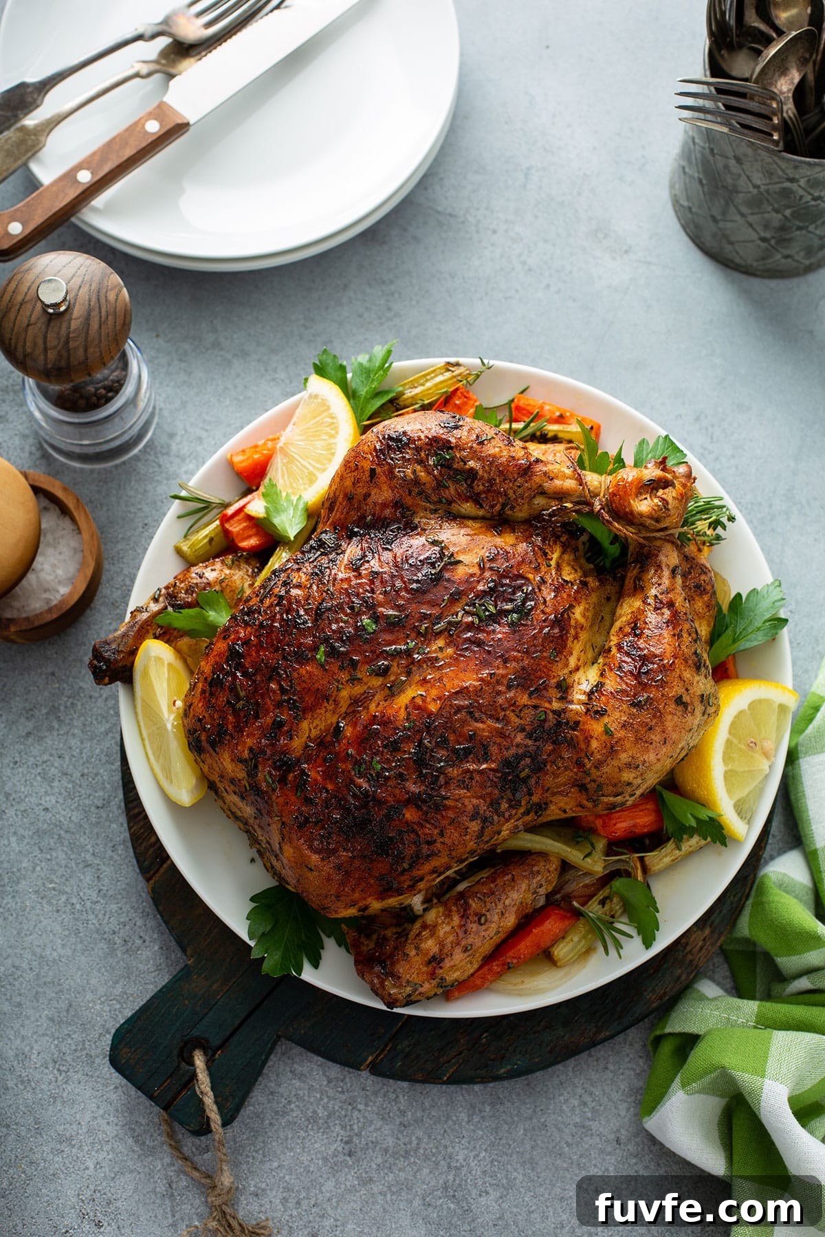 Herb-Butter Roast Chicken Recipe for Juicy Crispy Skin 12 Top view of a roasted chicken with vegetables on a white plate.