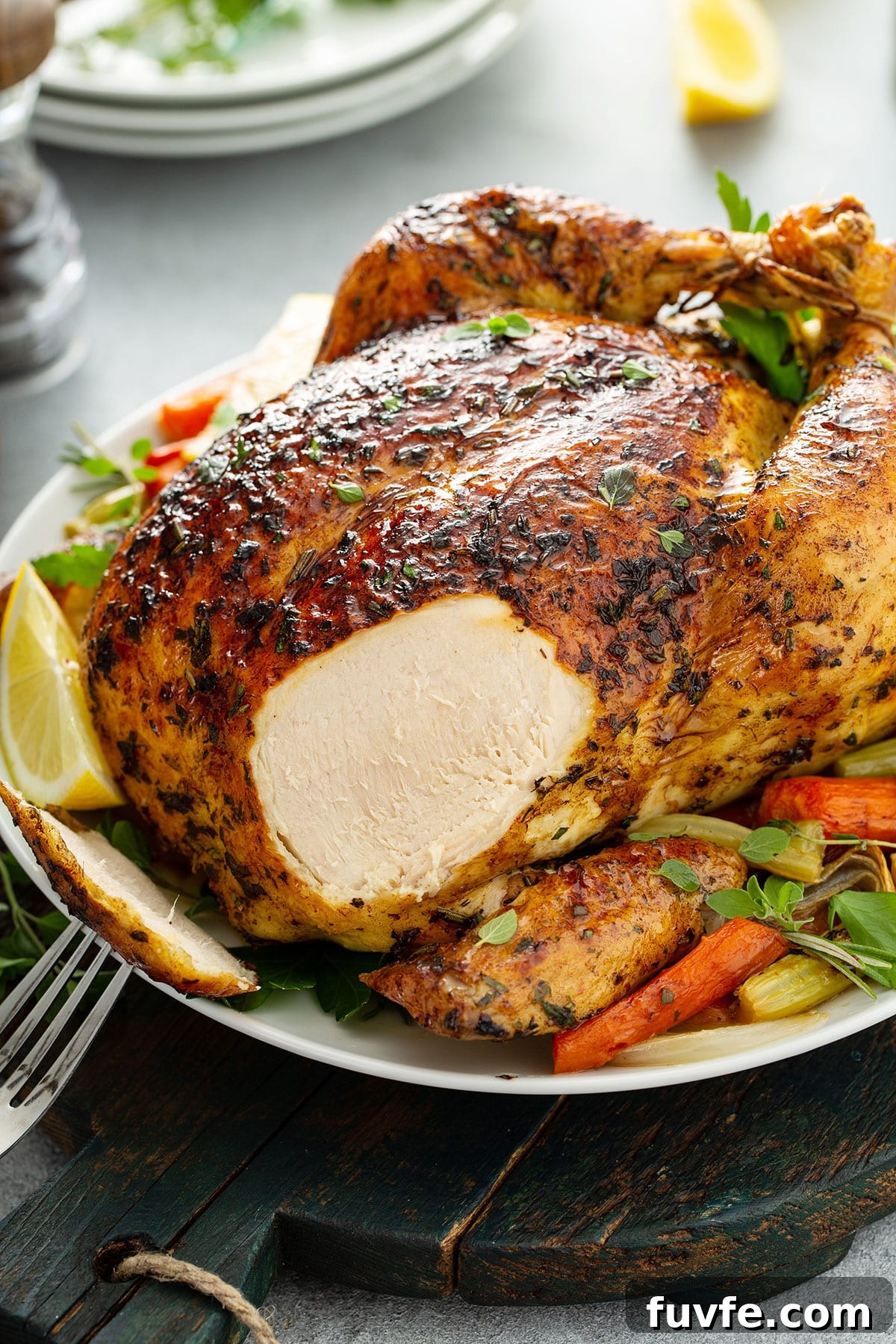 Herb-Butter Roast Chicken Recipe for Juicy Crispy Skin 10 A whole roast chicken with a piece of breast sliced off on a white plate.