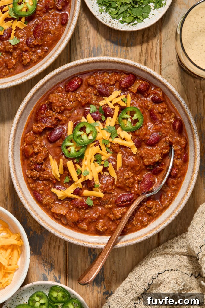 Guinness chili with ground beef in a bowl with cheese and jalapeno slices.