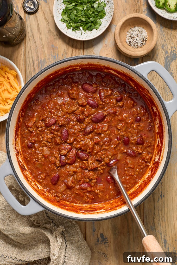 Guinness beef chili in a dutch oven with serving spoon digging in.