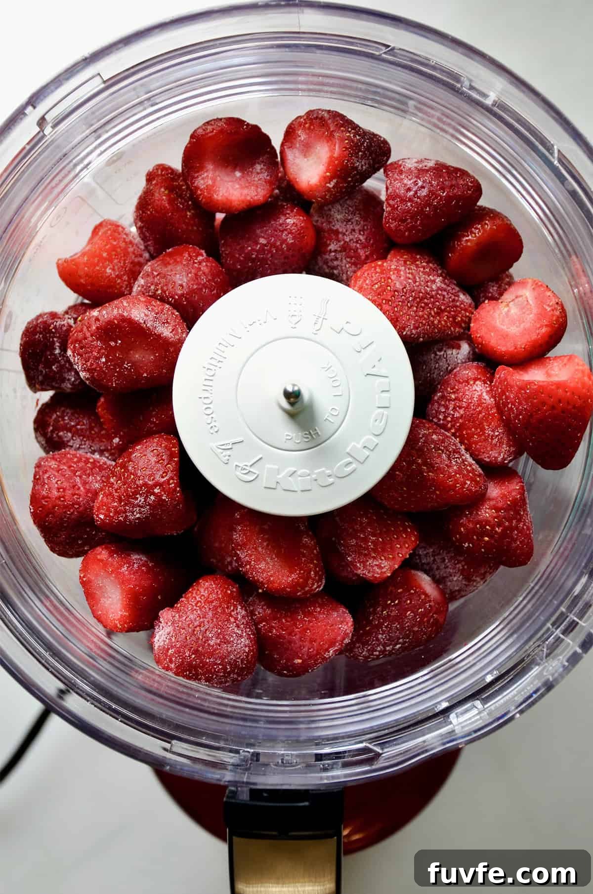 Quick Strawberry Frozen Yogurt Recipe Ready in 5 Minutes 4 Frozen strawberries in the bowl of a food processor.