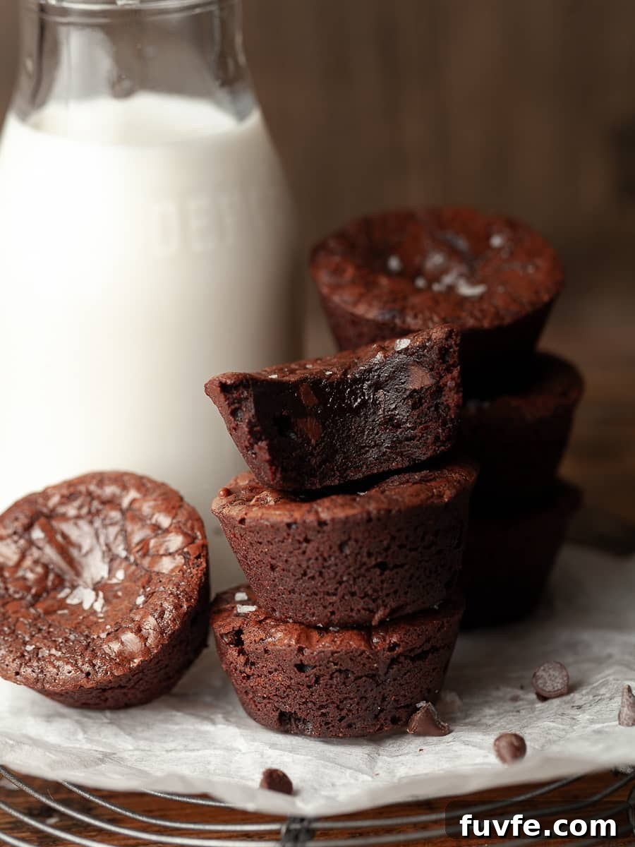 a stack of brownie bites next of a bottle of milk