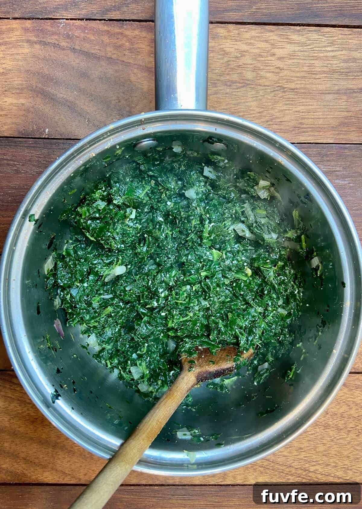Spinach in a small pot, with a wooden spoon.