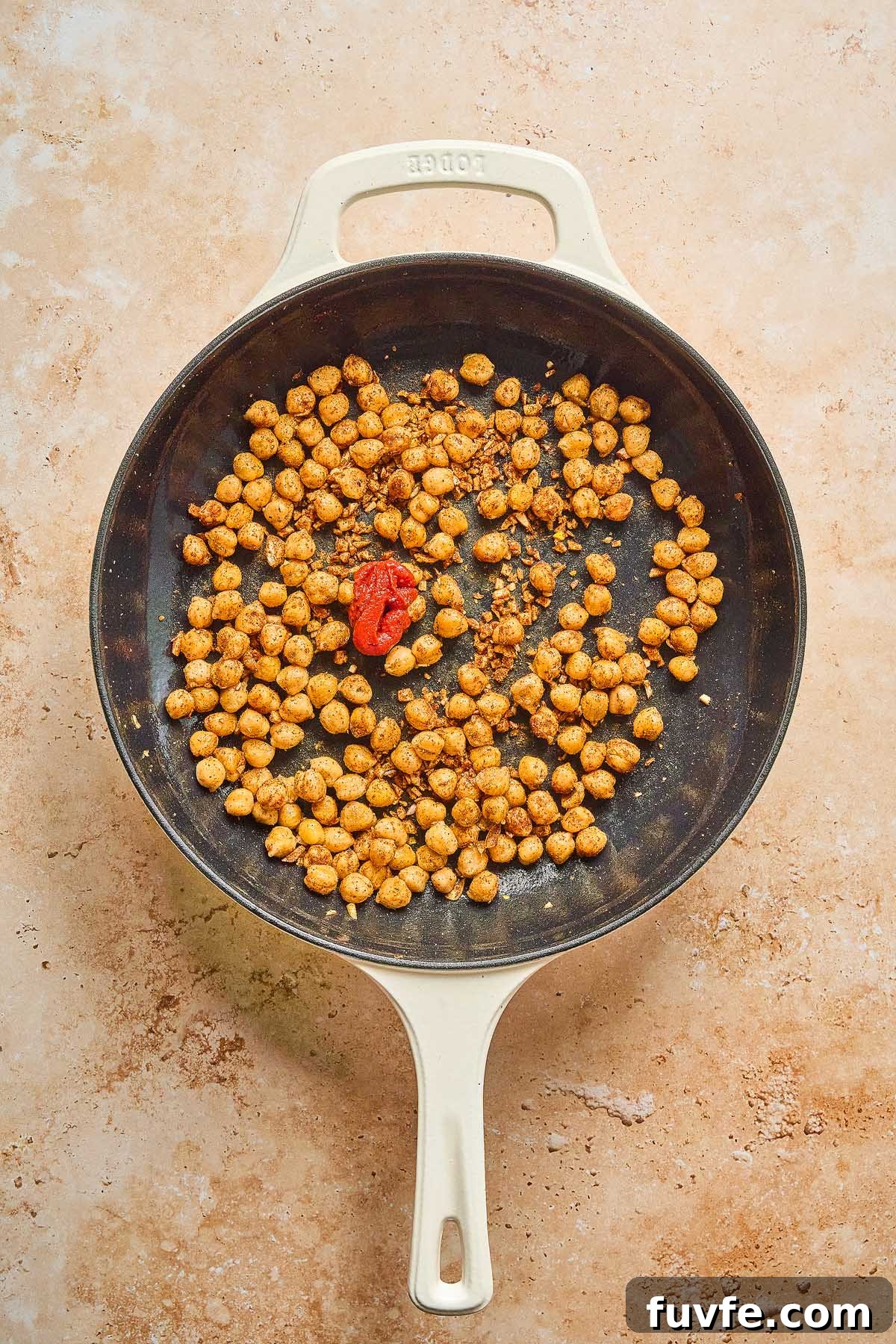 One-Pan Mediterranean Chickpea Skillet with Tomatoes & Spinach 16 Mediterranean chickpea skillet featuring seasoned chickpeas and a vibrant red chili pepper on a light-colored surface.