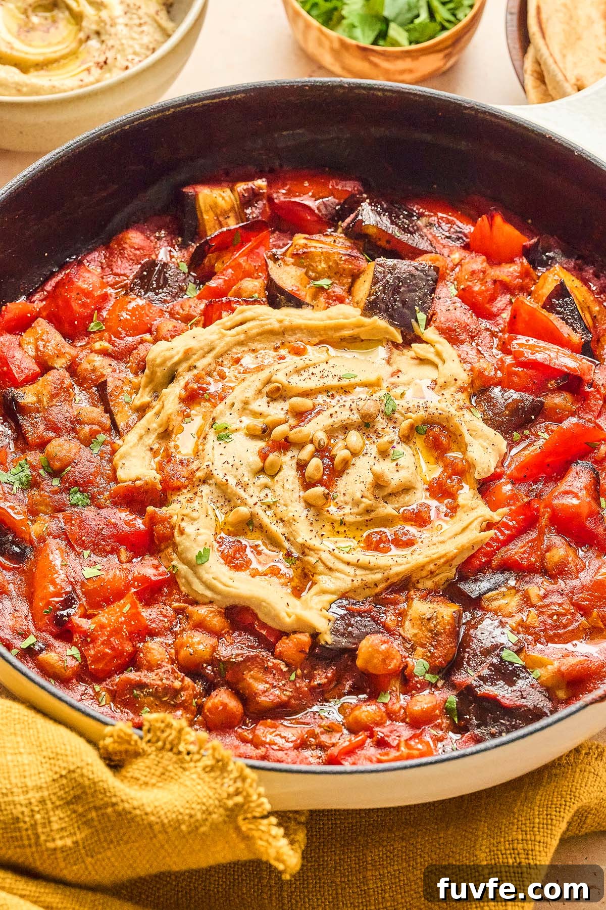 One-Pan Mediterranean Chickpea Skillet with Tomatoes & Spinach 7 Mediterranean chickpea skillet featuring a pan of roasted vegetables and chickpeas in tomato sauce, topped with creamy hummus and crunchy pine nuts.