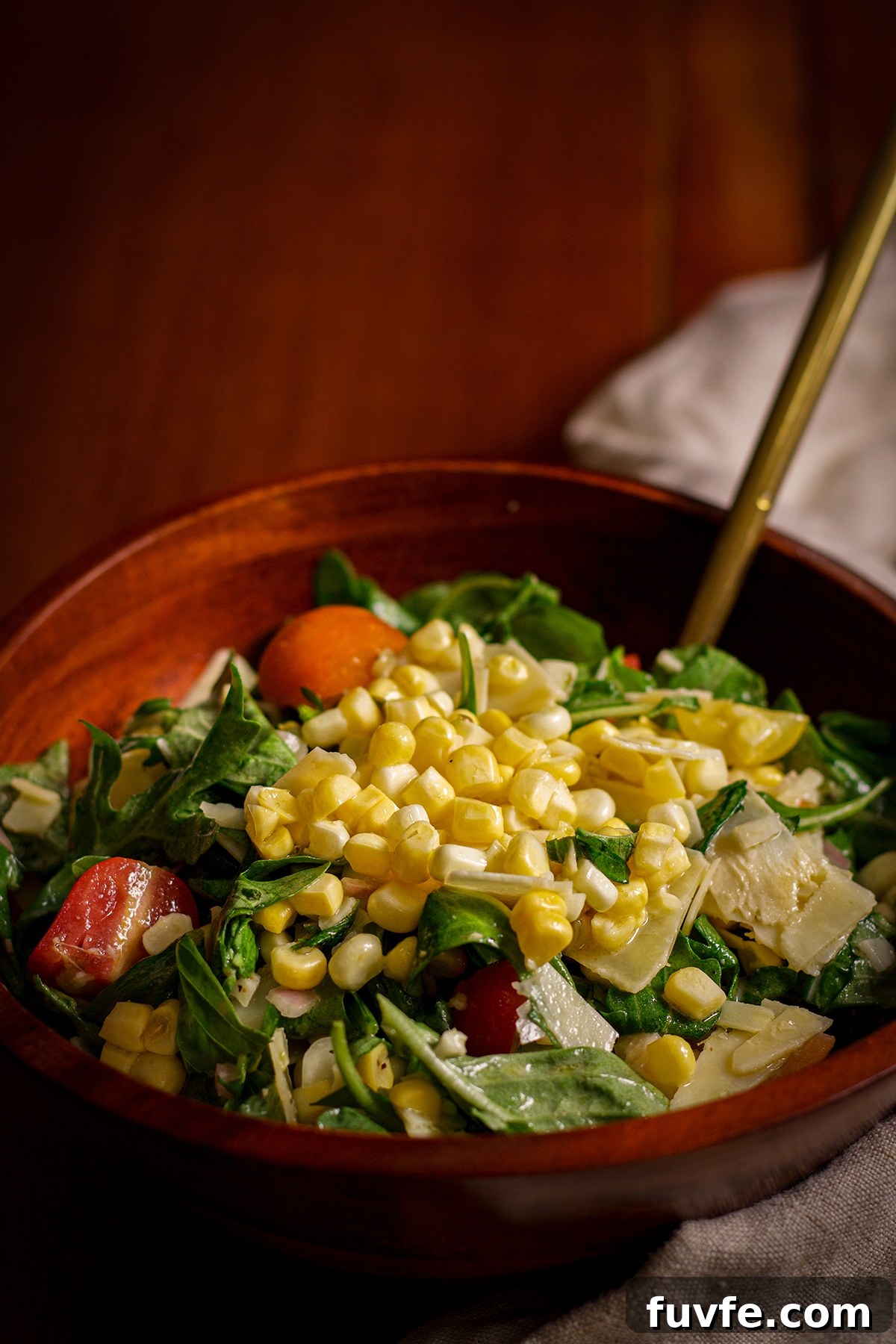 A bowl of fresh corn salad resting on a wood table.