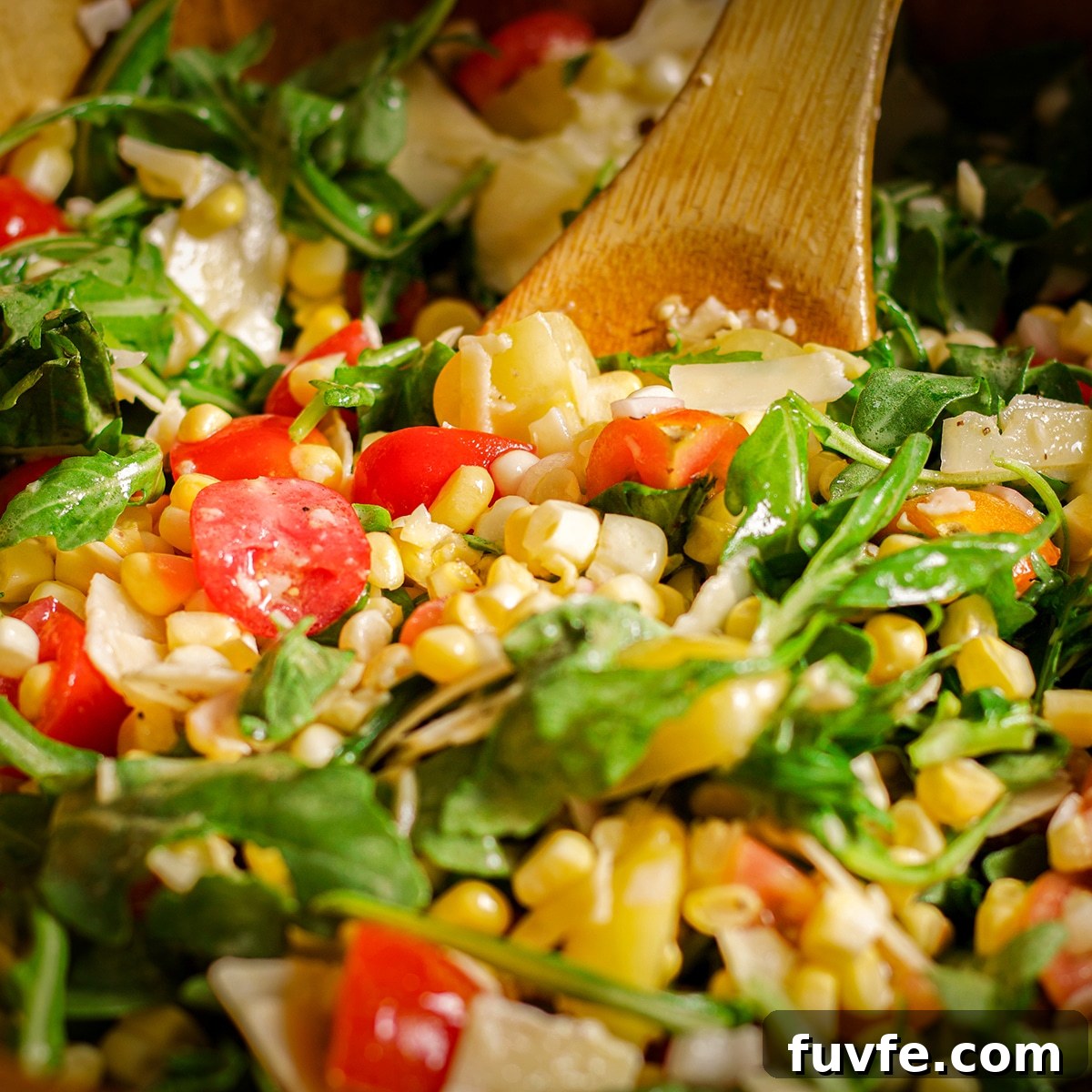 Using a wooden spoon to toss salad ingredients with vinaigrette.