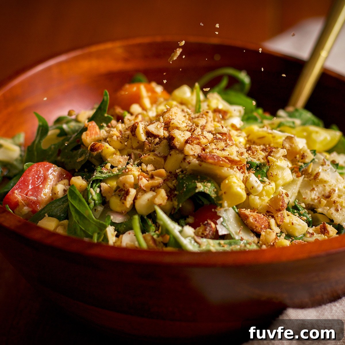 Sprinkling chopped almonds over a bowl filled with fresh corn salad.