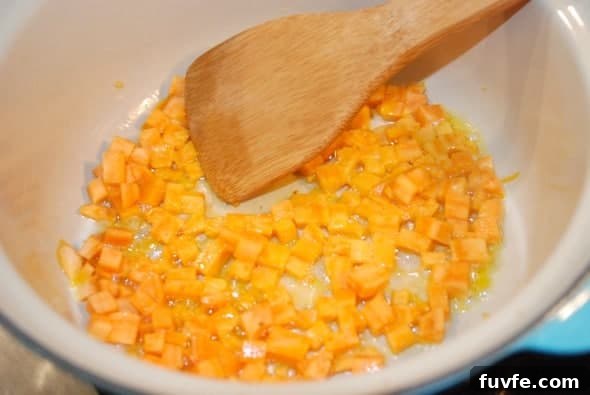 sweet potato sautéing in a pan with a wooden spoon