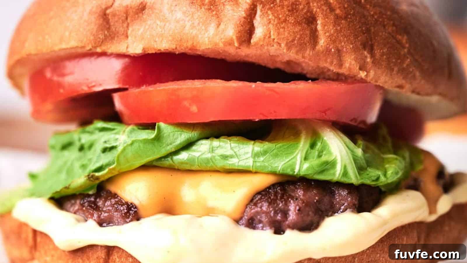 Close-up of a copycat smash burger with lettuce, tomato, and a thick beef patty on a sesame seed bun.