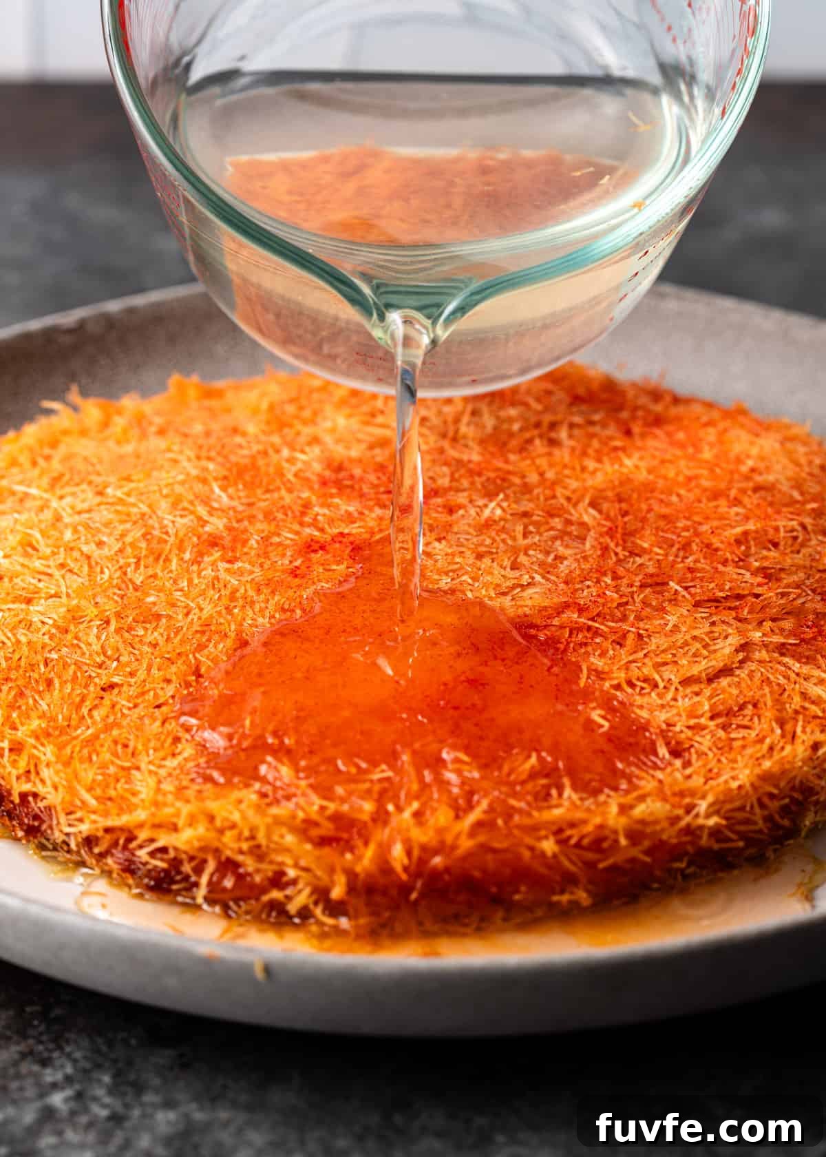 pouring sugar syrup on top of knafeh recipe