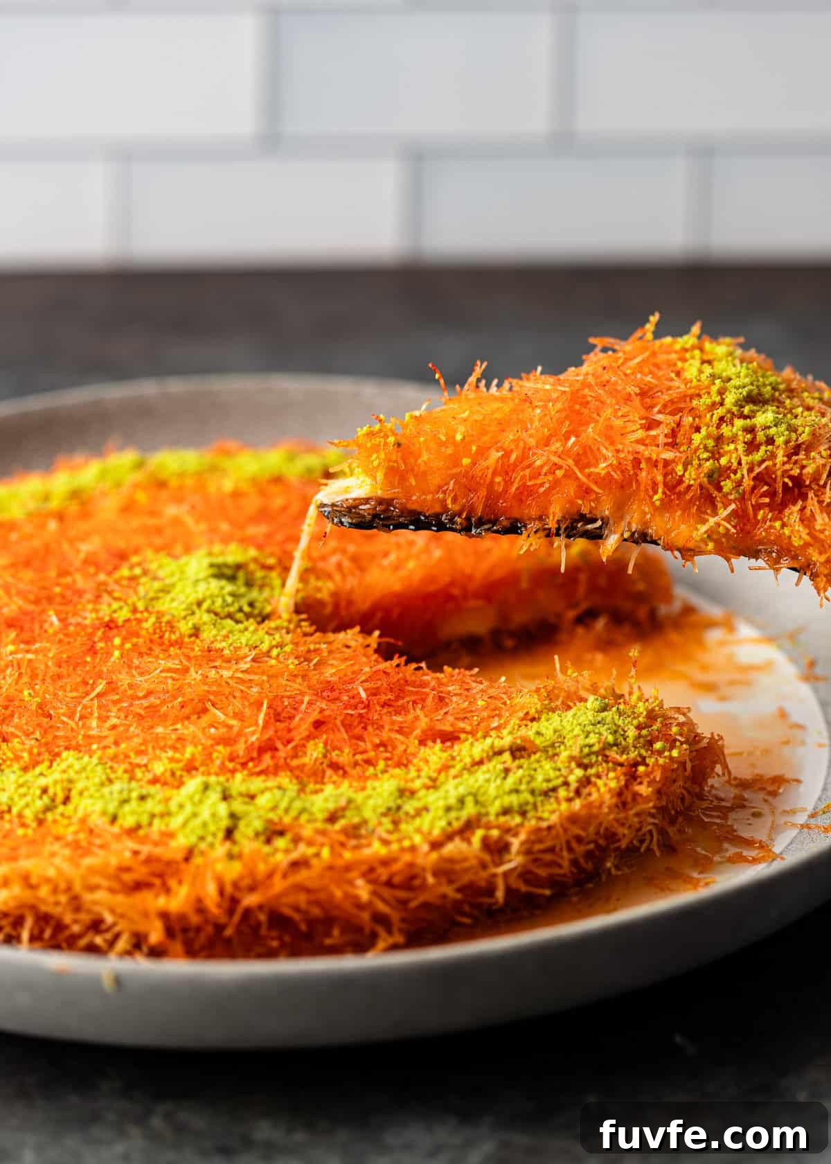 lifting a slice of knafeh out of a serving dish