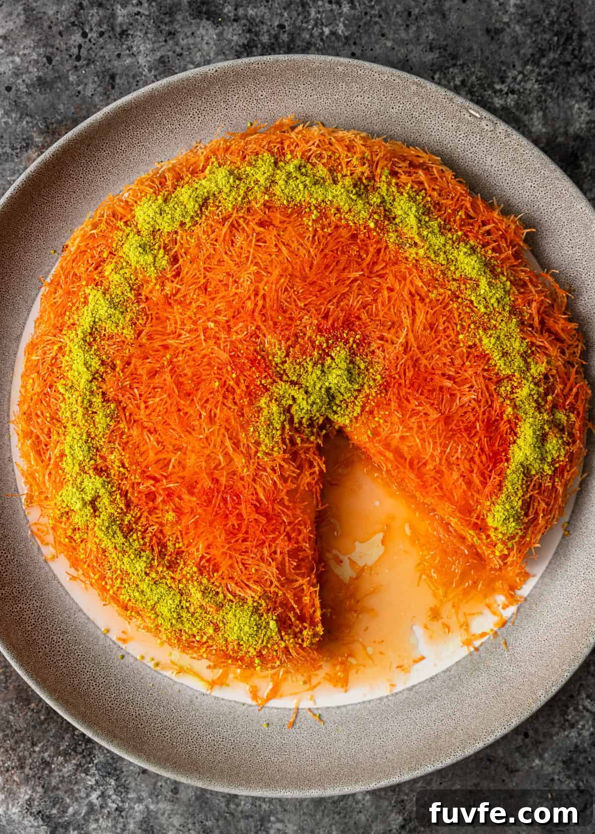 overhead: kunafa in a serving dish with a slice taken out of it