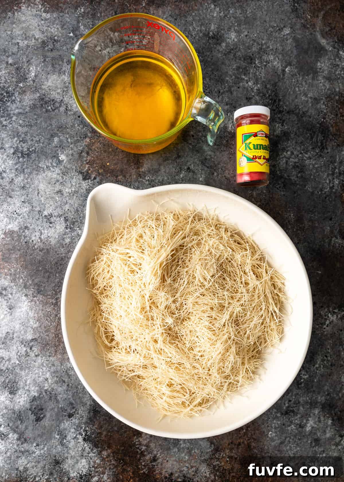 overhead: cut filo dough in a bowl next to a measuring cup with melted ghee