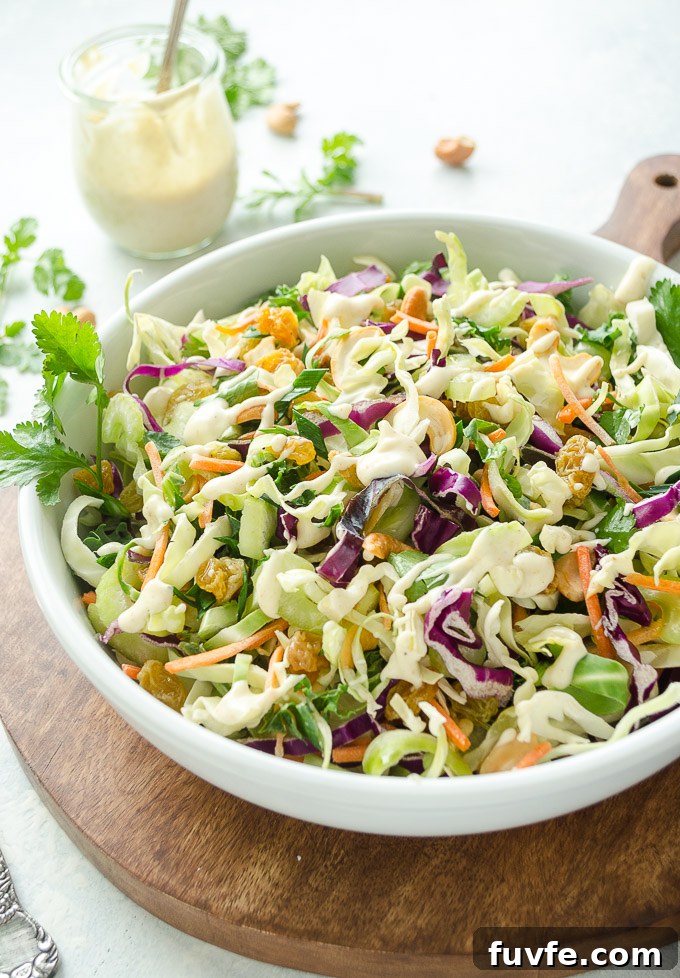 Curry coleslaw in a white bowl with dressing in a jar