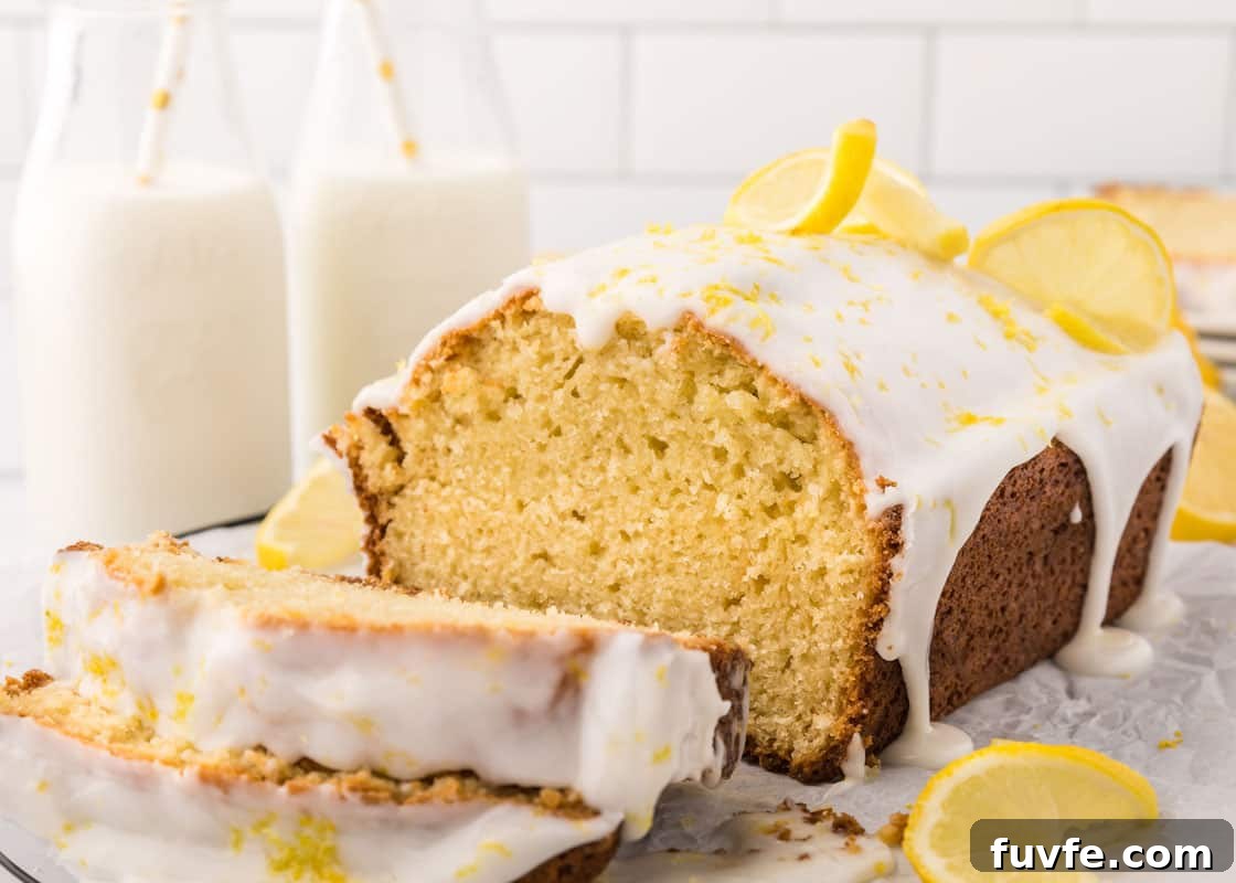 Slices of lemon loaf stacked on top of each other in front of the rest of the loaf.