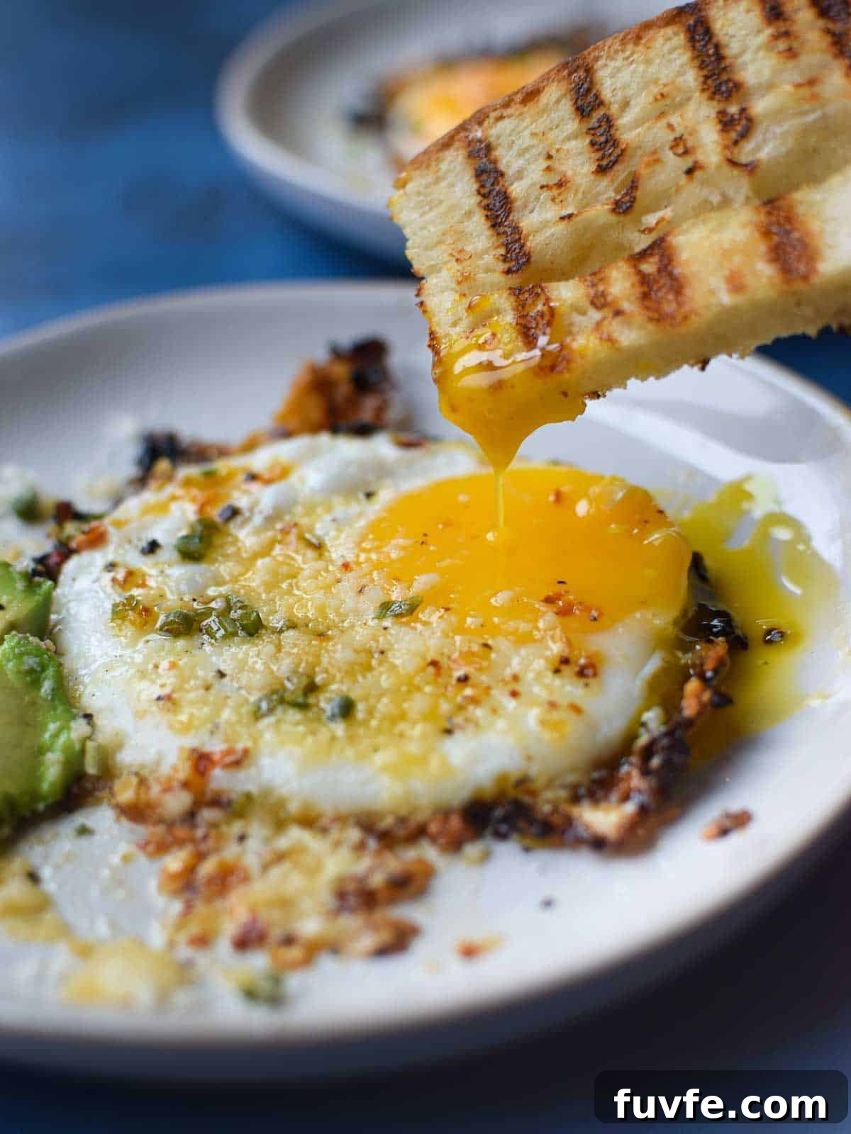 Parmesan Chili Crisp Fried Eggs: Crispy Sunny-Side with Heat 2 Fried egg with bread being dunked in a runny yolk.