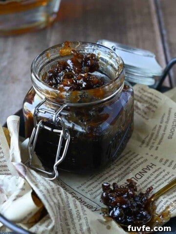 Bourbon and bacon jam in a clear glass jar on a tray lined with brown parchment paper.