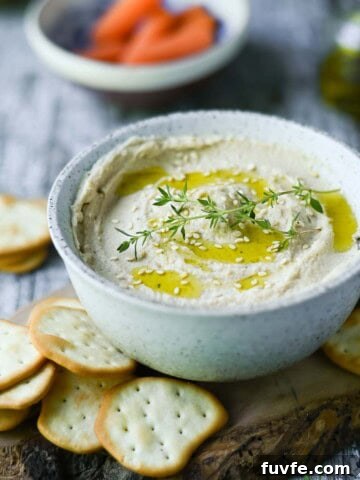Butter bean hummus in a white bowl, with crackers around it.