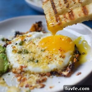 Parmesan Chili Crisp Fried Eggs: Crispy Sunny-Side with Heat 14 Fried egg with bread being dunked in a runny yolk.