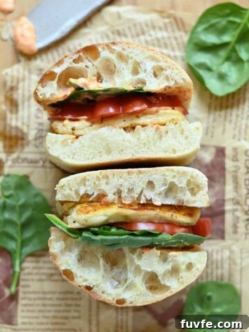 Overhead of two halloumi sandwiches on parchment paper with lettuce in the background.