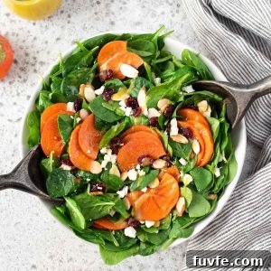 Persimmon salad in a bowl with salad servers