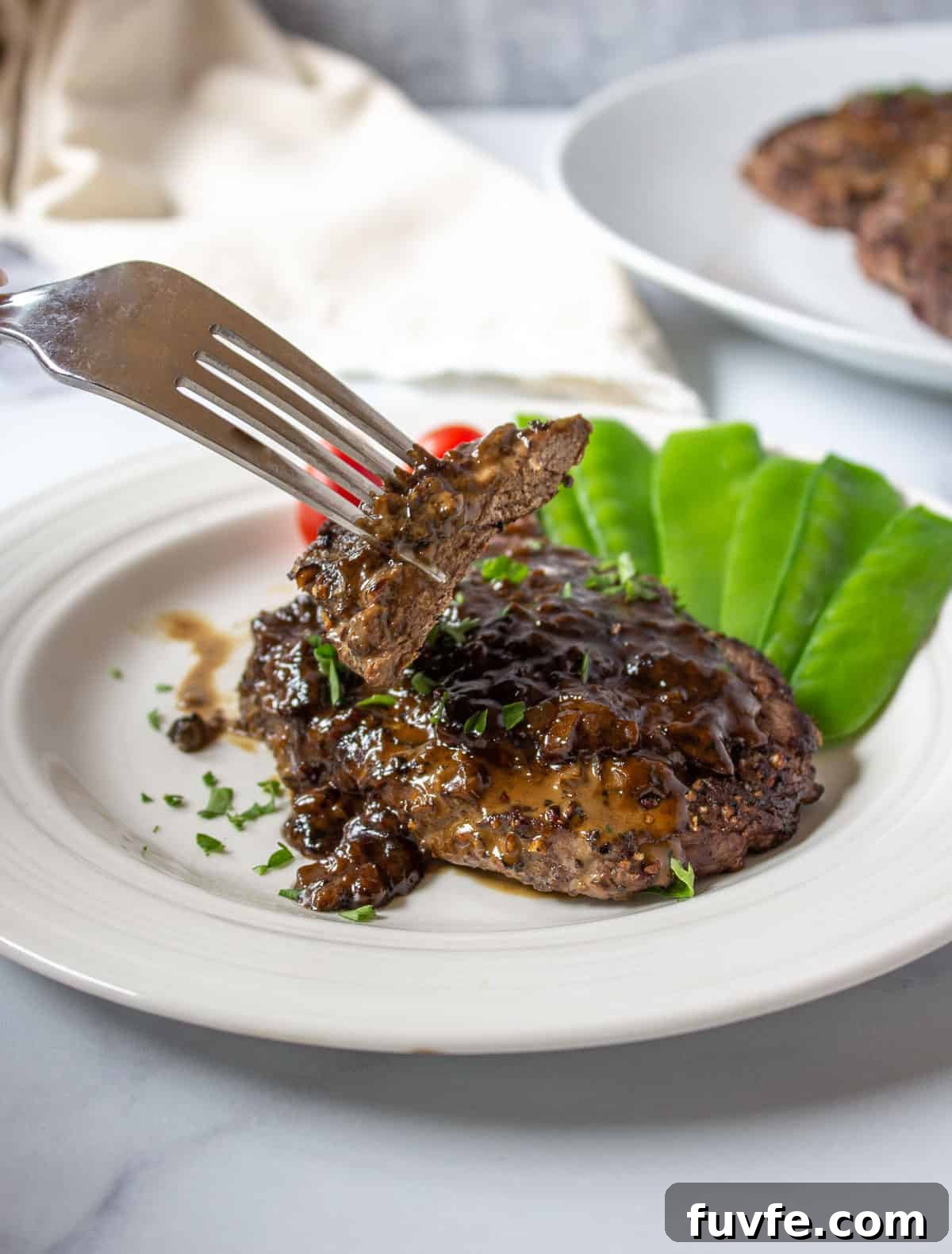 Elk Steak au Poivre Recipe: Peppercorn-Crusted Venison Steak 3 A slice of elk steak on a fork.