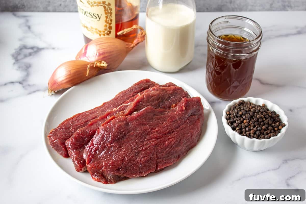 Elk Steak au Poivre Recipe: Peppercorn-Crusted Venison Steak 4 Raw elk steaks on a white plate next to a small bowl filled with peppercorns.