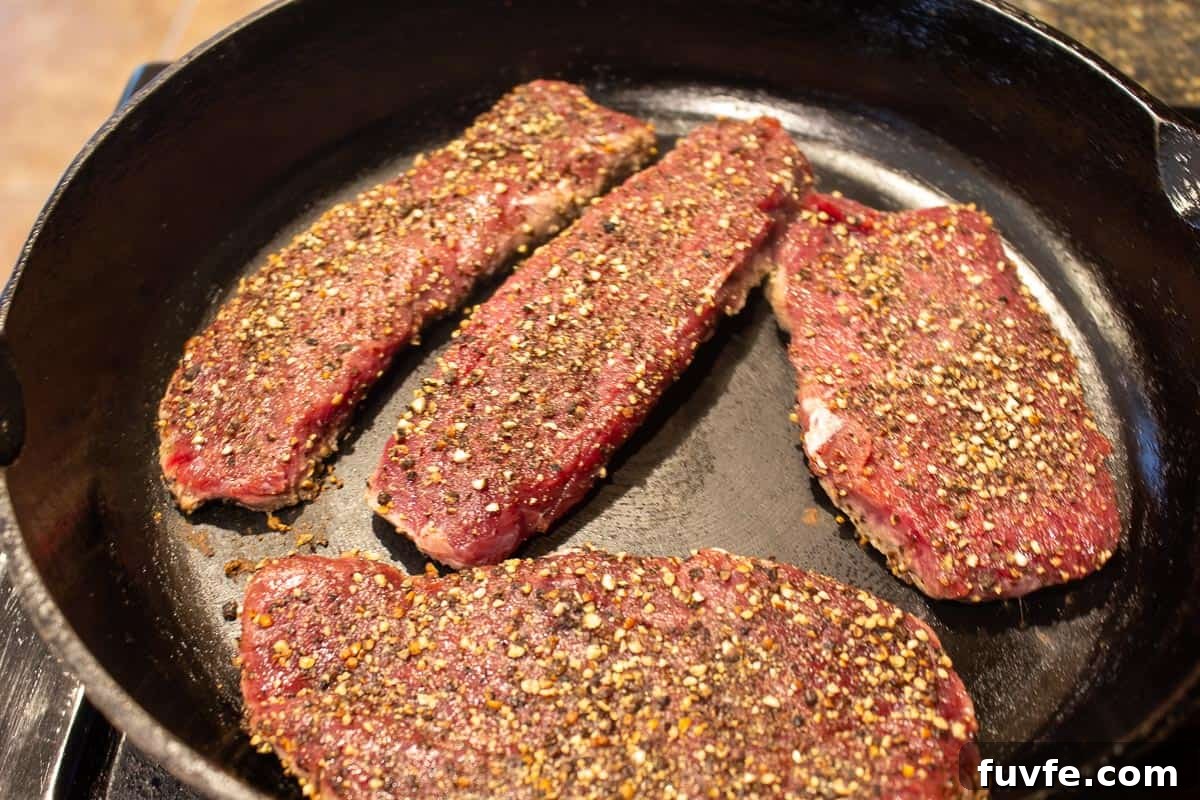Elk Steak au Poivre Recipe: Peppercorn-Crusted Venison Steak 6 Elk steaks in a black cast iron pan.