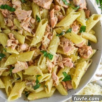 overhead shot of pasta alla salmone in pasta dish with fork and bowl of parmesan on the side