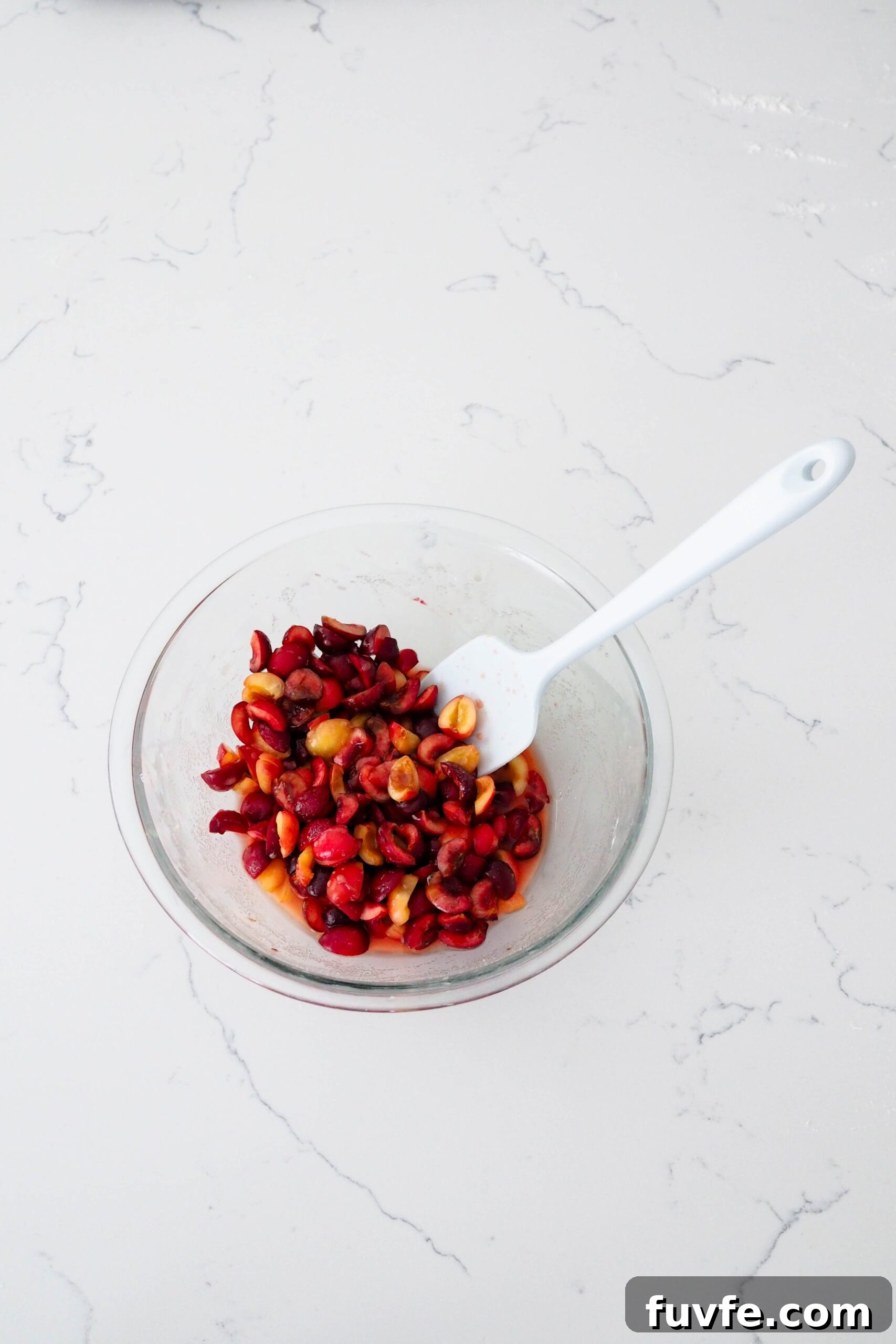 A bowl of macerated cherries on a quartz counter.