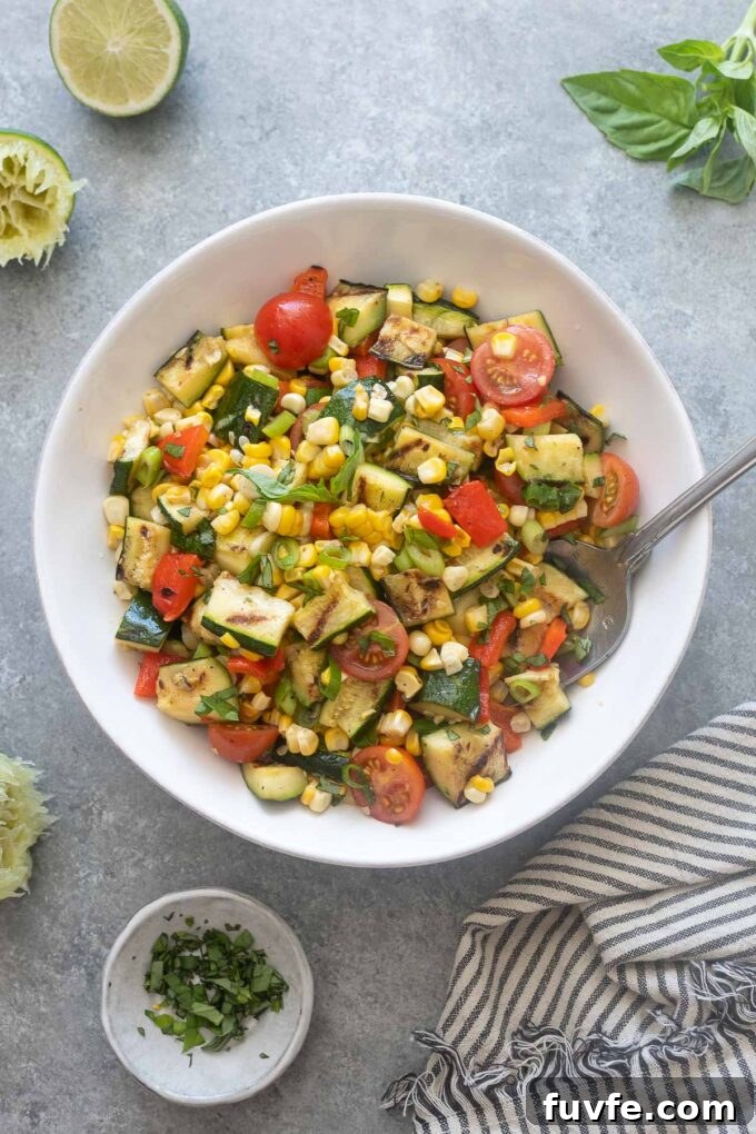 Grilled Zucchini and Corn Salad with Lime and Feta 2 Grilled zucchini and corn salad in a bowl with serving spoon.