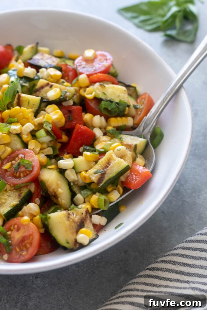 Grilled Zucchini and Corn Salad with Lemon Herb Dressing 6 Serving spoon digging into corn and zucchini salad.