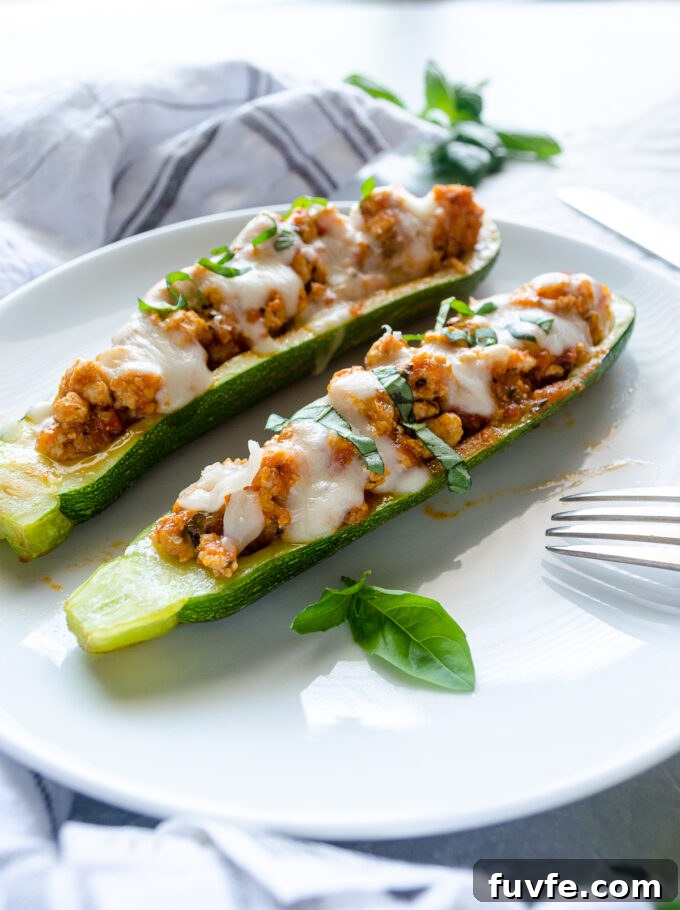 Ground meat stuffed zucchini boats on a plate.