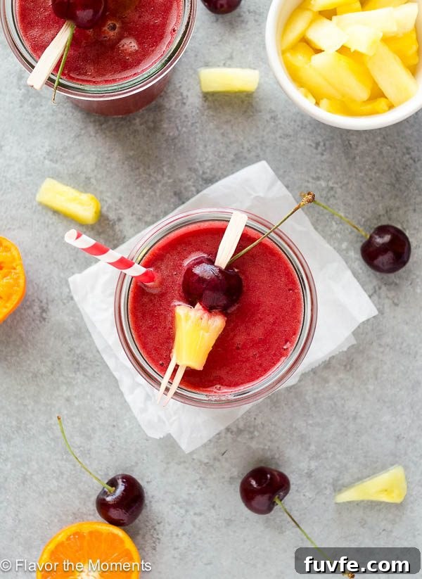 Overhead shot of cherry pineapple smoothie in jar with straw