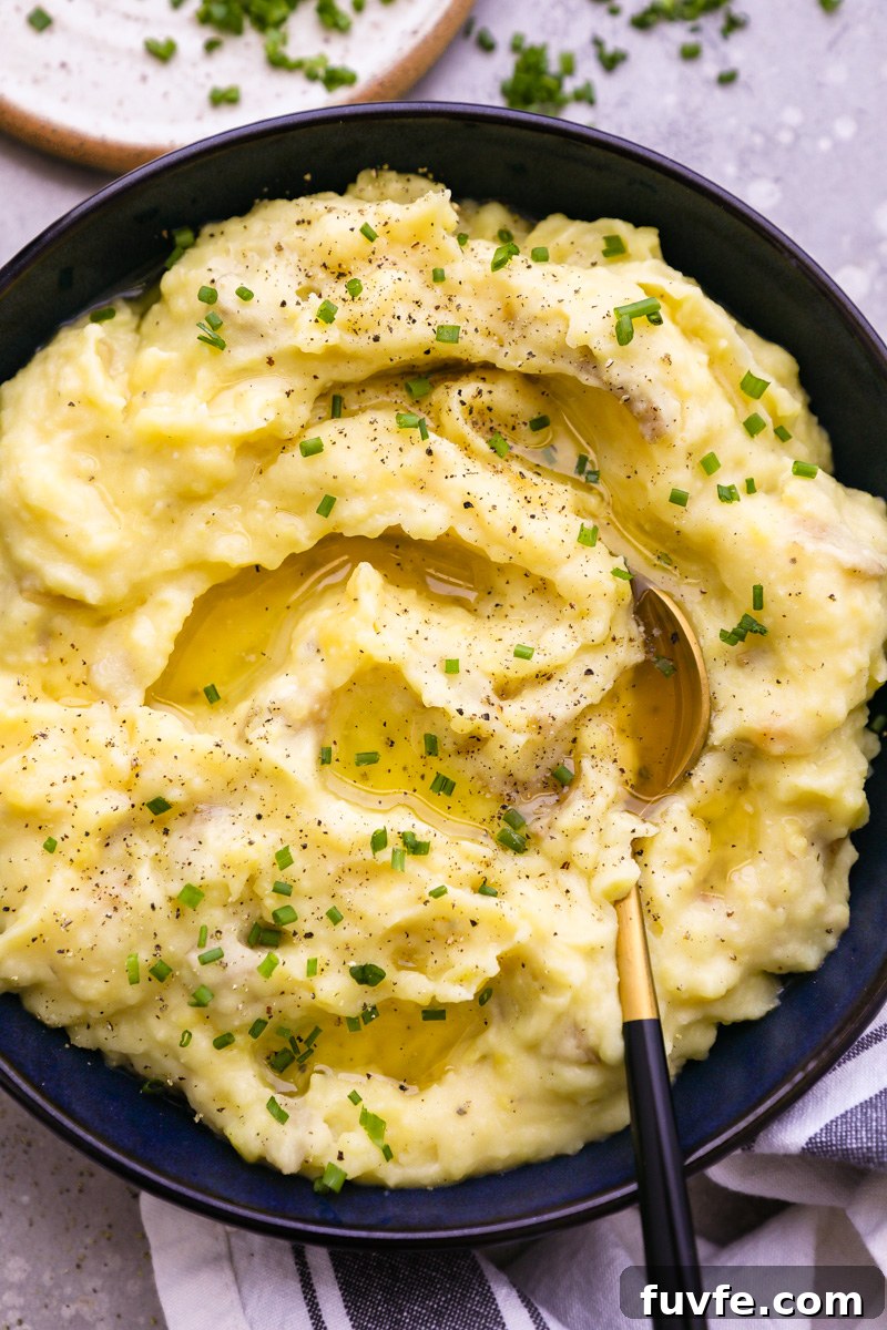 A close up photo of roasted garlic mashed potatoes topped with melted butter and chopped chives