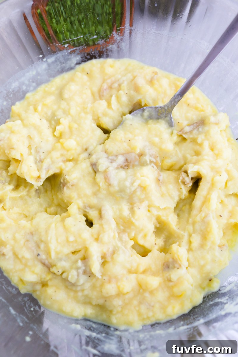 A large clear mixing bowl filled with freshly made roasted garlic mashed potatoes