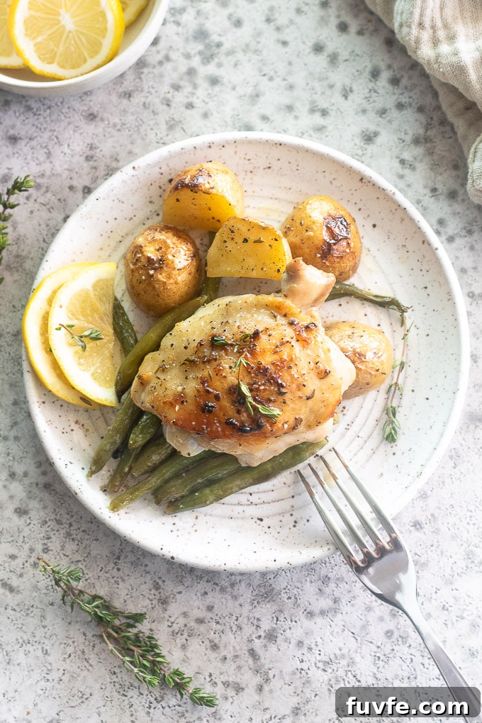 Lemon garlic chicken thighs on a plate with vegetables.