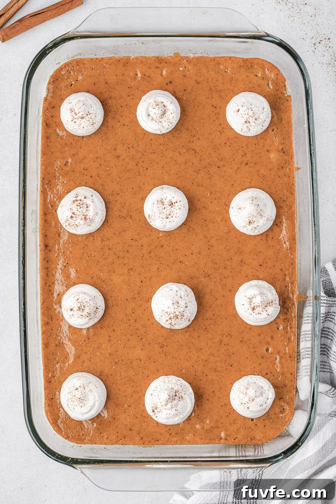 Pumpkin pie bars in baking dish with whipped cream dollops