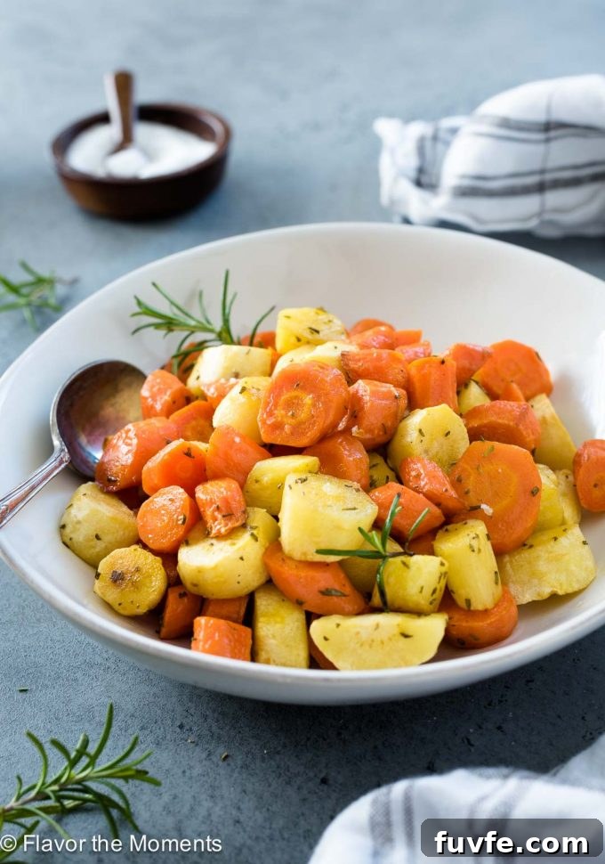 Roasted carrots and parsnips in a white bowl with spoon