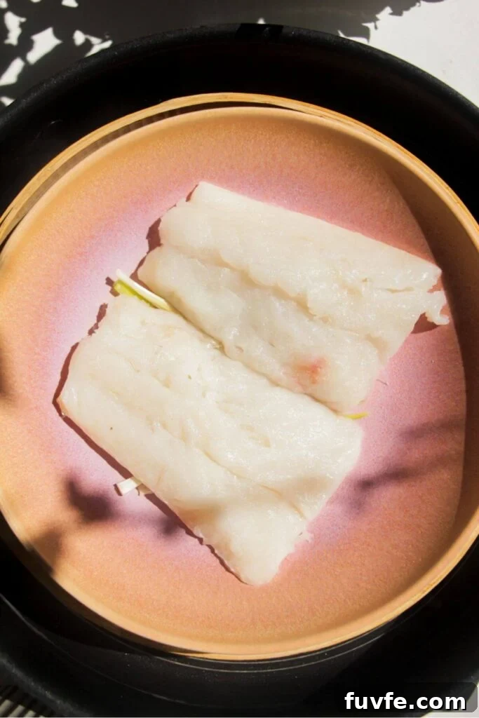 Two fish fillets in a pink bowl in a steamer basket.