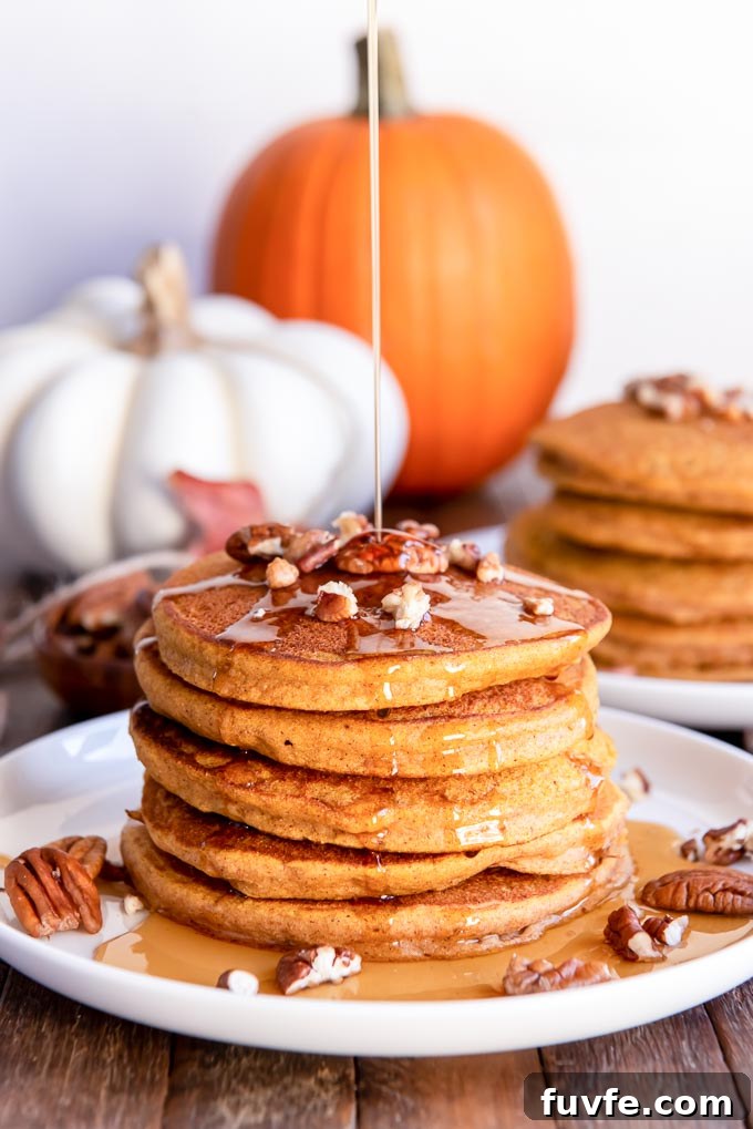 Stream of maple syrup pouring over a stack of whole wheat pumpkin pancakes