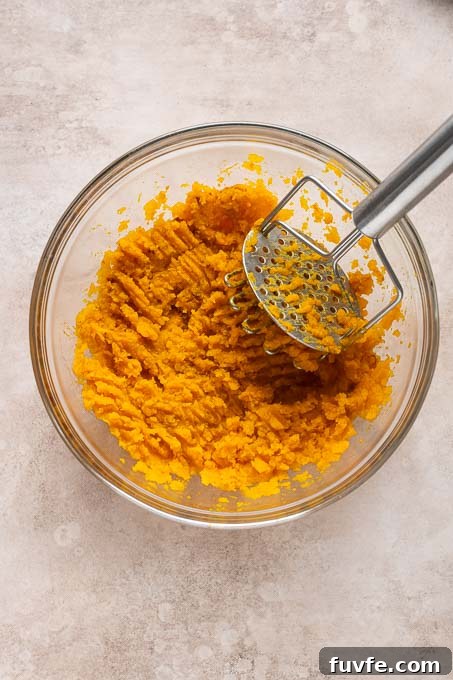 Velvety Kabocha Squash Mash Recipe 7 Mashed kabocha in a large bowl with potato masher.