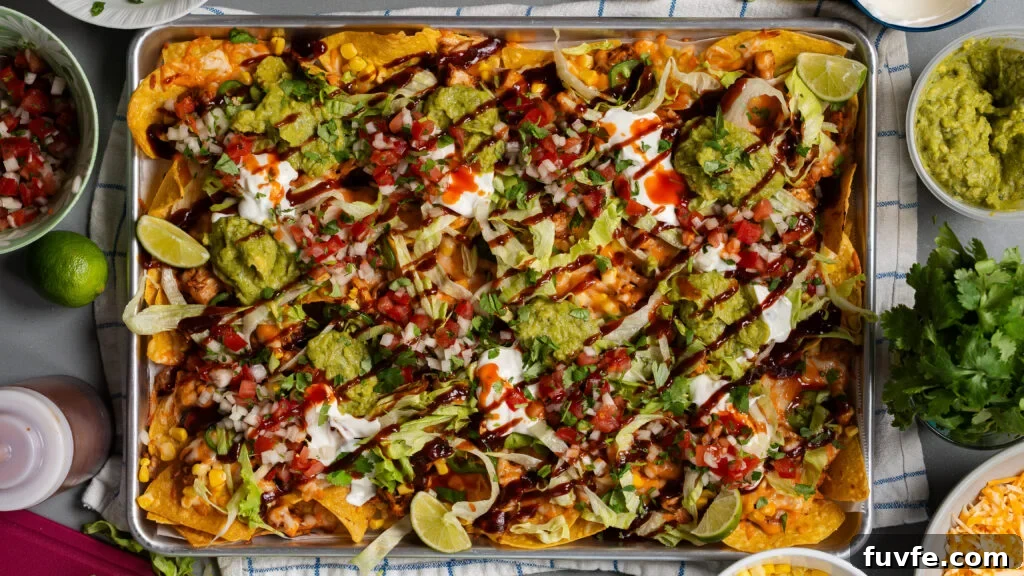BBQ Rotisserie Chicken Nachos with Cheesy Jalapeño Topping 9 Loaded BBQ chicken nachos on a sheet pan with shredded cheese.