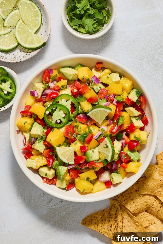 Avocado mango salsa in a serving bowl surrounded by tortilla chips.