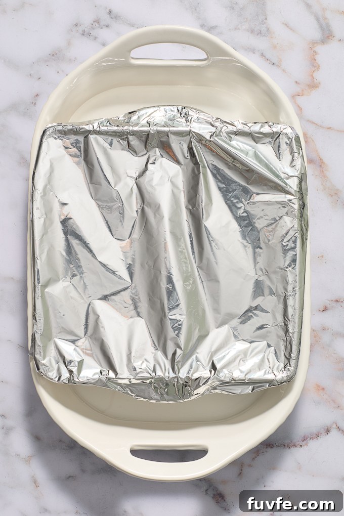 Corn cake in baking dish in water bath covered with foil.