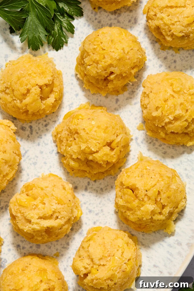 Scoops of Mexican corn cake on a white platter with cilantro.