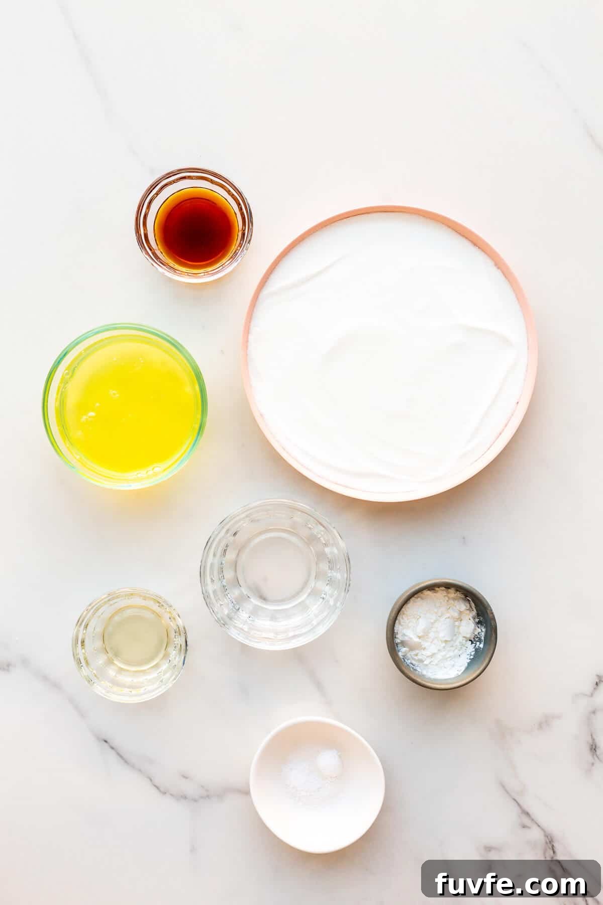 Classic Pavlova Recipe: Crispy Meringue with Fresh Fruit 3 Ingredients measured out to make a pavlova from scratch from egg whites, super fine sugar, cream of tartar, cornstarch, vinegar, vanilla, and salt.