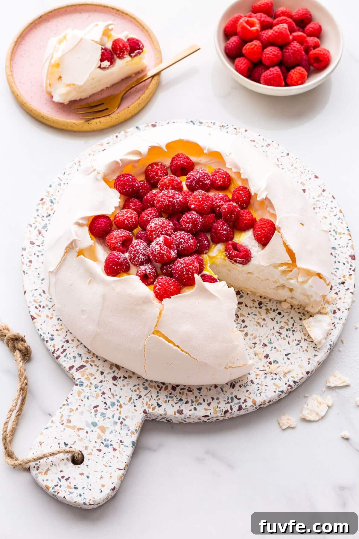 Classic Pavlova Recipe: Crispy Meringue with Fresh Fruit 9 Pavlova cake filled with whipped cream, lemon curd, and raspberries being served.